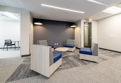 Casual breakout space with blue armchairs and a small round table.