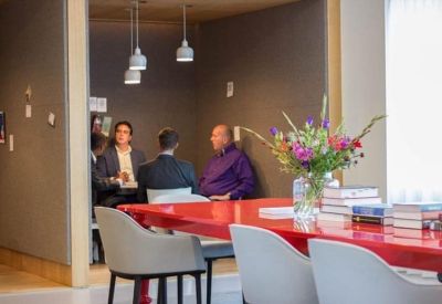 People chatting in a cozy breakout booth with a red table and floral arrangement.