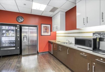 Breakroom kitchen area with a red accent wall, vending machine, and modern cabinetry.