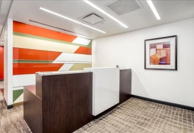 Office reception area with a dark wood and white front desk and colorful abstract wall art.