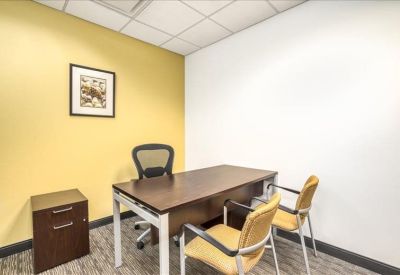 Private office with a dark wood desk, yellow feature wall, and guest chairs.