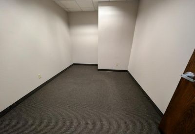 Small, empty private office suite with neutral walls and dark carpeting.