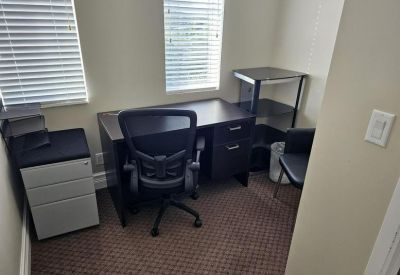 Single person workstation with a black desk, ergonomic chair, and silver filing cabinet.