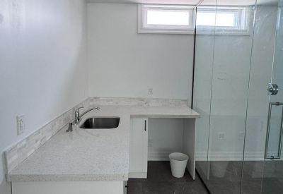 Small office with a sleek white desk and three black chairs.
