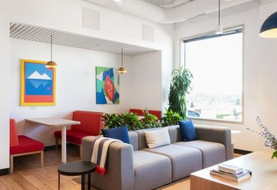 Lounge area with a grey sofa, red booth seating, and abstract art pieces.