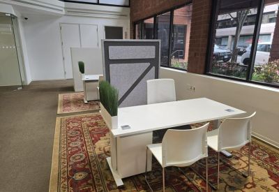 Open-plan area with white desks, modern chairs, and a decorative rug