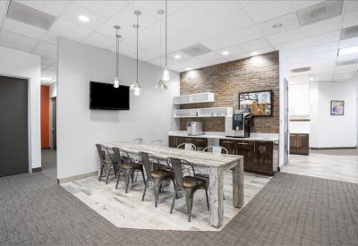 Communal kitchen area with a long rustic wooden table and coffee station.