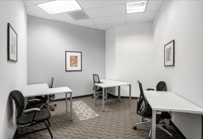 Private internal office suite with three white desks and framed wall art.