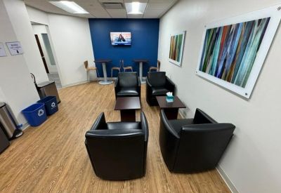 Lounge area with black leather armchairs and a blue accent wall with TV.