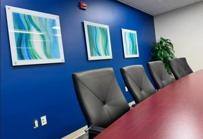 Modern boardroom with a dark wood table and blue feature wall with art.