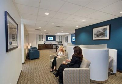 Bright communal lounge area with plush armchairs and white curved privacy pods.
