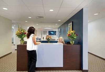Modern reception area with a dark wood desk, colorful flowers, and a deep blue feature wall.