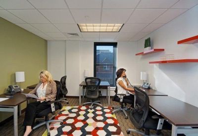 Collaborative workspace featuring a vibrant geometric rug and contemporary orange shelving.