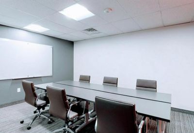 Modern conference room featuring a long gray table and ergonomic leather chairs.