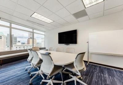 Modern conference room with a white table, ergonomic chairs, and wall-mounted TV.