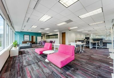 Vibrant coworking area with bright pink lounge chairs and multiple workstations.