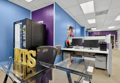 Workstation area featuring a glass desk with MTS signage and a black ergonomic chair.