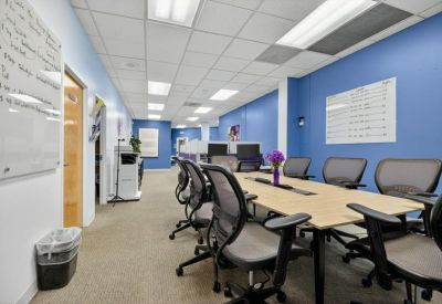 Long conference table with black mesh chairs in a room featuring blue and purple walls.