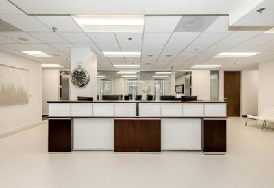 Sleek white and wood reception desk under bright modular ceiling lights.