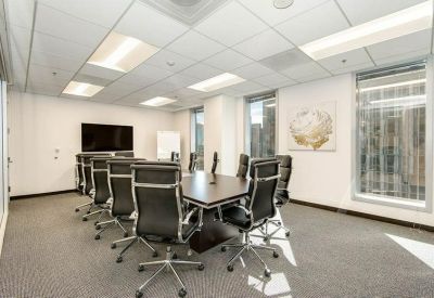 Spacious boardroom with a dark wood table, black leather chairs, and large windows.
