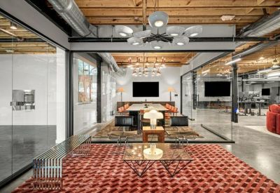 Spacious open-plan lounge with a red patterned rug and glass-walled meeting rooms.