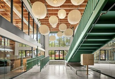 Modern lobby area with a teal staircase and large spherical pendant lights hanging from a timber ceiling.
