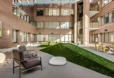 Sun-drenched multi-level atrium with a tiered green lawn area and modern seating.