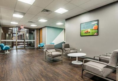 Spacious reception lounge with mid-century modern armchairs and wood-style flooring.