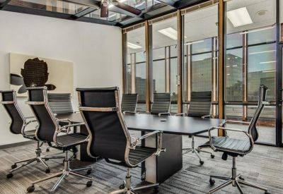 Professional conference room featuring a large black table and glass walls under a skylight ceiling.
