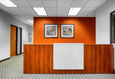 Reception area with a wood-panelled front desk and a vibrant orange feature wall.