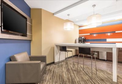 Breakout area featuring a high table, stools, and orange wall accents.