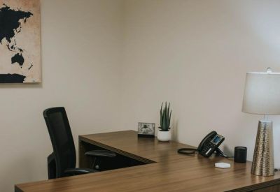 Executive office desk with a leather chair and world map decor.