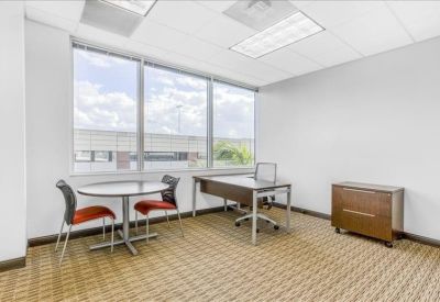 Private office suite with a desk, round meeting table, and large window.