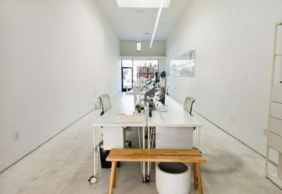 Long open-plan office with white desks, a wooden bench, and a skylight.