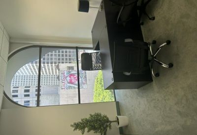 Private office with a dark wood desk and a large arched window overlooking the city.