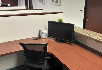 Modern workstation with an L-shaped wood-tone desk and ergonomic mesh chair.