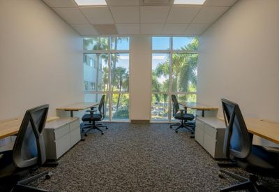 Bright four-person office suite with individual desks, storage cabinets, and floor-to-ceiling windows.