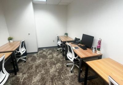 Spacious office suite with multiple workstations and patterned brown carpeting.