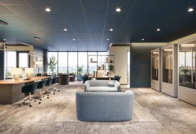 Modern coworking space with a long wooden communal table and light blue lounge seating.