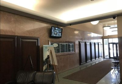 Long corridor and lounge area with marble walls, leather chairs, and a directory board.