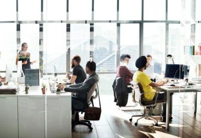 Bright, open-plan office with multiple workstations and floor-to-ceiling windows.