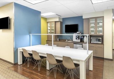 Communal break area with a long white counter, coffee machine, and blue and yellow walls.