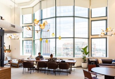 Spacious coworking lounge with high ceilings, warm pendant lighting, and floor-to-ceiling city views.
