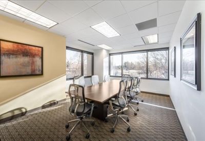 Spacious boardroom with a large wooden table, mesh chairs, and floor-to-ceiling windows.