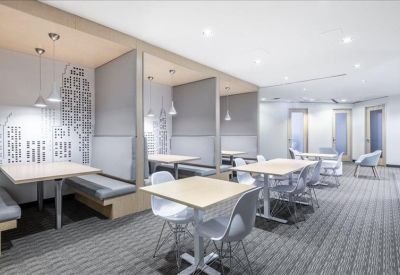 Bright communal breakroom with booth seating, cafe tables, and city skyline wall art.