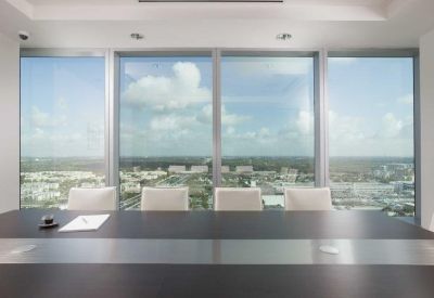 Close-up of a dark wood boardroom table set against floor-to-ceiling windows.