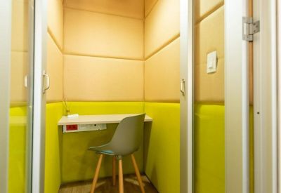 Private phone booth or focus room with sound-absorbing yellow walls and a grey task chair.