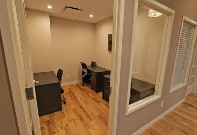 Private two-person office suite with dark wood desks and hardwood flooring.