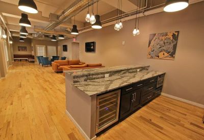 Bright coworking lounge with hardwood floors and a marble-topped island.
