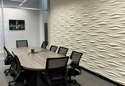 Modern conference room with a textured wave-pattern feature wall and grey chairs.